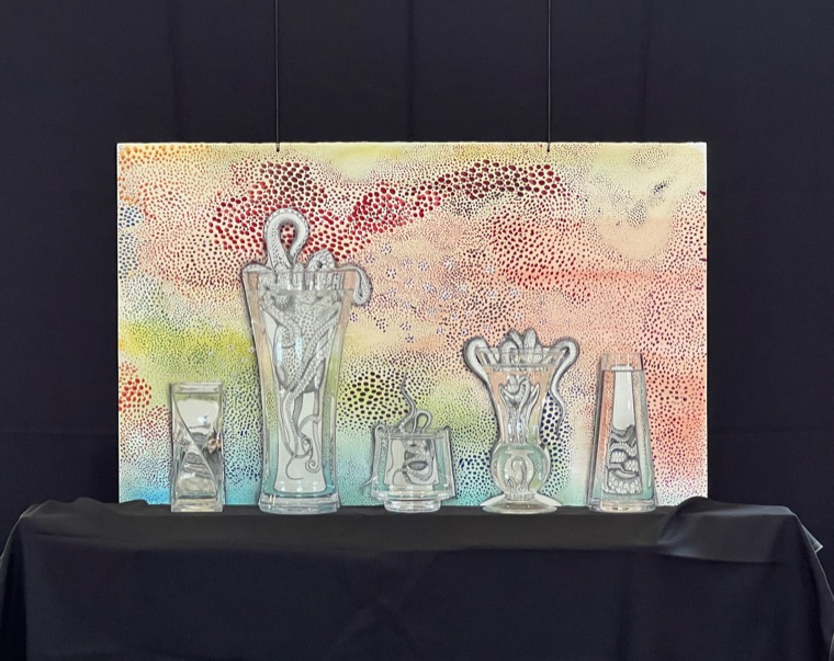 A finished mixed-media painting of five glass vessels containing figures, set against a ground of dense multicoloured dots, photographed hanging above a black-draped table.